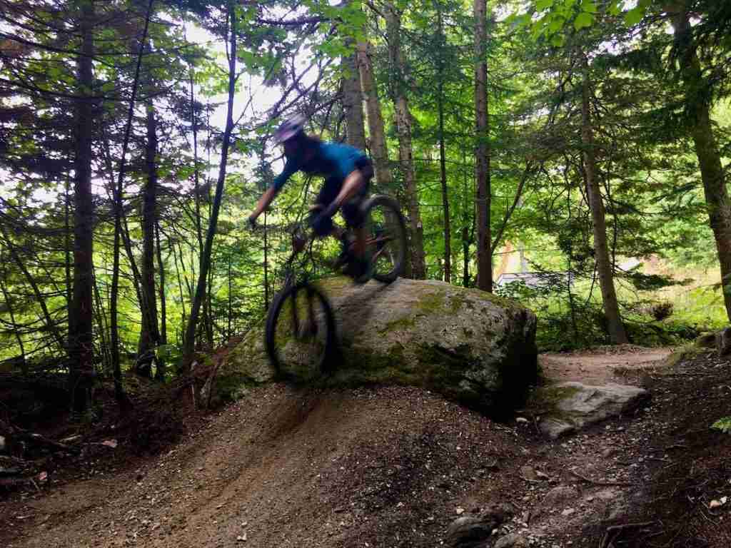 Becky riding mountain bike over rock roller at Killington Bike Park in Vermont