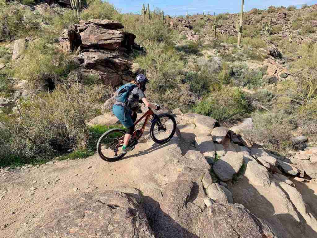Female mountain biker on National Trail in Phoenix, Arizona about to roll down a steep and rocky section of trail